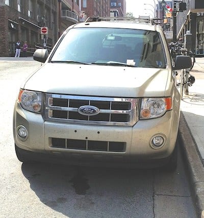 PARKED INCORRECTLY: Vehicle parked on steep hill with wheels parallel to the curb.